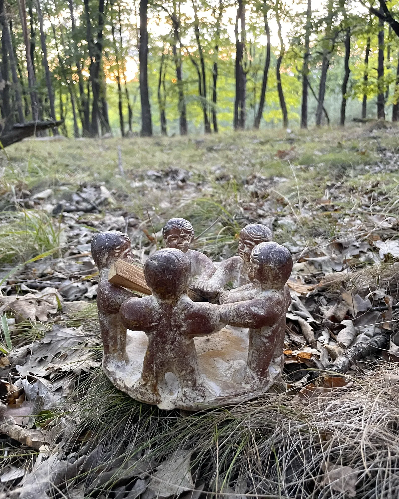 Kerzenhalter aus Tonfiguren im Kreis auf Herbstlaub im Wald